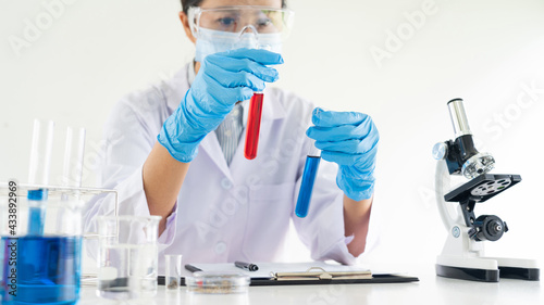 scientists researching in laboratory in white lab coat, gloves analysing, looking at test tubes sample, biotechnology concept