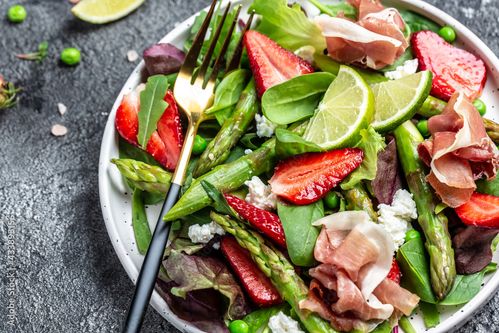 Diet menu. Healthy salad of fresh green asparagus, strawberry, rocket and cottage cheese, place for text. Top view