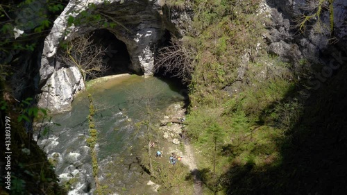 Cave system in wonderful wild karst valley, Rakov Skocjan, Slovenia. People enjoying in beautiful limestone gorge on sunny day. Handheld, real time