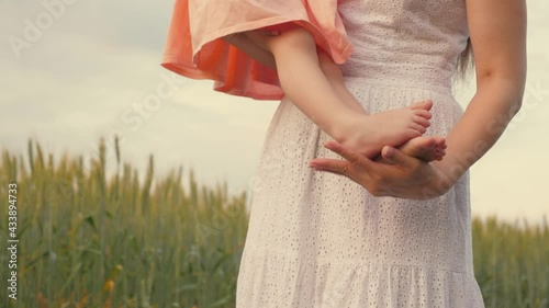 Kid, mom walk travel together outdoor recreation. Family, baby and mommy are walking in park in summer. Little daughter sits barefoot in her mothers arms, mother walks with child in field in spring. photo