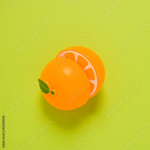 orange halves plastic toy fruit on green background 