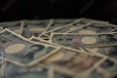 Blurred focus of pile of Japanese money in 1000 yen bills and 10000 yen bills on black background in soft focus
