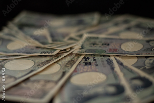 Blurred focus of pile of Japanese money in 1000 yen bills and 10000 yen bills on black background in soft focus