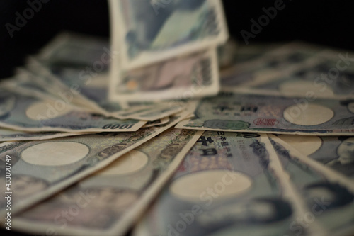 Blurred focus of pile of Japanese money in 1000 yen bills and 10000 yen bills dropping on black background in soft focus