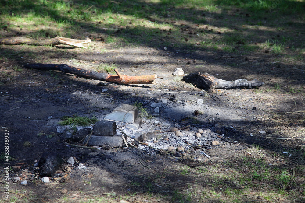 Fototapeta premium Abandoned extinguished fire place white bricks ring on ground close up with sun shadows, outdoors picnic leisure, empty campsite fireplace safety on a spring day, picture with copy space