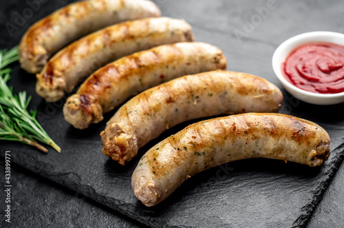 grilled sausages with spices on a stone background