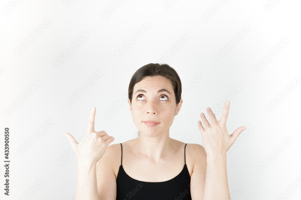 Young beautiful woman pointing up with fingers while thinking at white empty background Young beautiful woman pointing up with fingers while thinking at white empty background