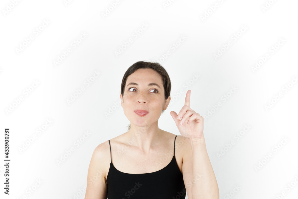Young beautiful woman pointing up with fingers while thinking at white empty background Young beautiful woman pointing up with fingers while thinking at white empty background