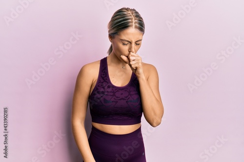 Beautiful blonde woman wearing sportswear over pink background feeling unwell and coughing as symptom for cold or bronchitis. health care concept.