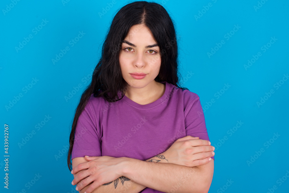 young beautiful tattooed girl wearing blue t-shirt standing against blue background Pointing down with fingers showing advertisement, surprised face and open mouth young beautiful tattooed girl wearing blue t-shirt standing against blue background Pointing down with fingers showing advertisement, surprised face and open mouth