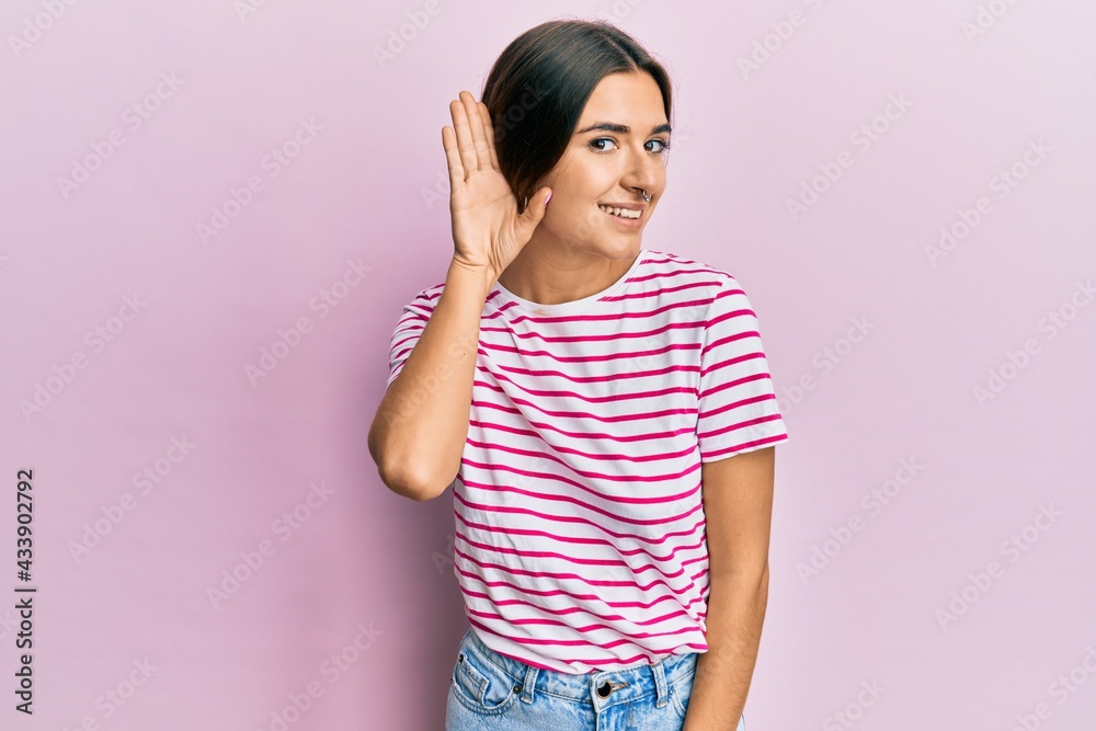 Young hispanic woman wearing casual clothes smiling with hand over ear listening and hearing to rumor or gossip. deafness concept. Young hispanic woman wearing casual clothes smiling with hand over ear listening and hearing to rumor or gossip. deafness concept.