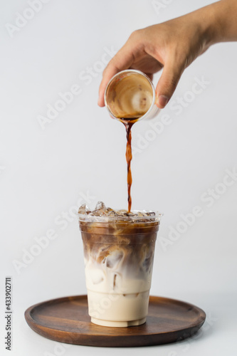 Konstfotografi pouring espresso shot coffee into a glass of milk to become an iced latte on the
