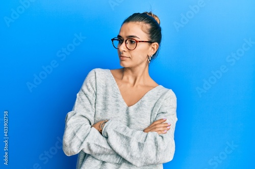 Young hispanic woman wearing casual clothes looking to the side with arms crossed convinced and confident
