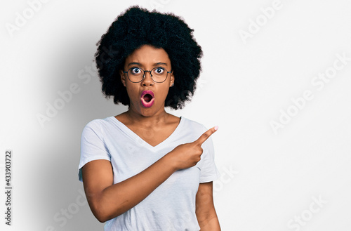 Young african american woman wearing casual white t shirt surprised pointing with finger to the side, open mouth amazed expression.