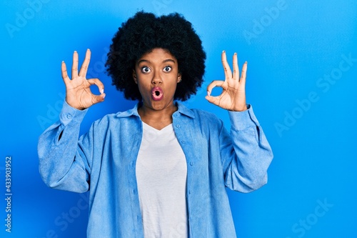 Young african american woman wearing casual clothes looking surprised and shocked doing ok approval symbol with fingers. crazy expression