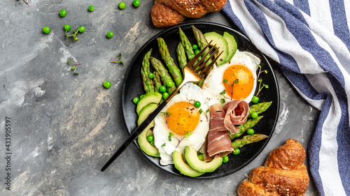 asparagus, avocado, fried egg with prosciutto salad, ketogenic diet lunch concept. top view