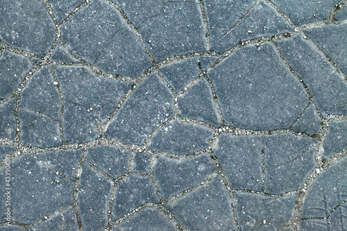 Detail of cracked asphalt pavement surface. Chapped footpath texture. Pavement deffects, overhead shot. Large cracks on asphalt footway. Cracky blue walkway. Crannied way, closeup shot. Rimous walk