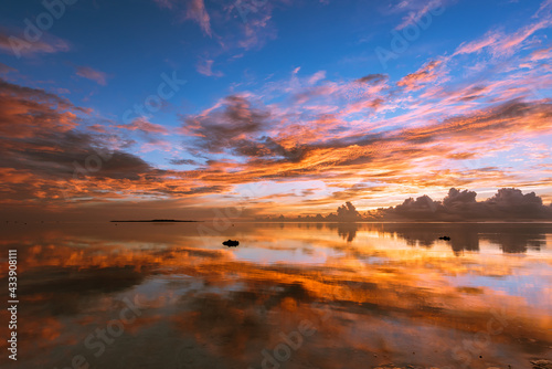 Splendid seascape with a colorful sunrise, shades of yellow, orange, pink and blue with reflecting like a mirror in the smooth surface water of the sea. Iriomote Island.
