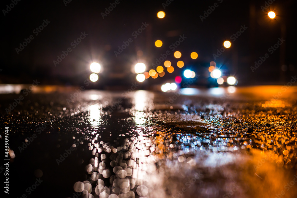 Rainy night in the big city, the cars traveling towards the headlights illuminate the road. Close up view from the level of the dividing line