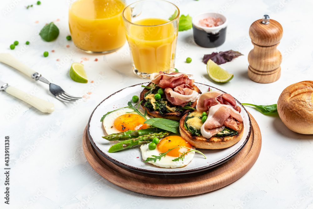 Healthy breakfast set grilled bun with spinach and cheese, asparagus, jamon, ham, prosciutto and fried egg. fresh juice, The concept of delicious and healthy food. top view
