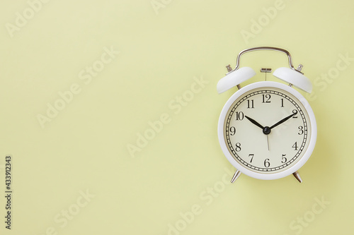 White Alarm Clock on Pastel Yellow Minimalist Background on Right Frame