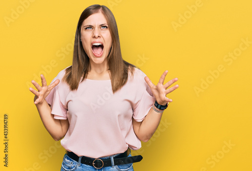Beautiful caucasian woman wearing casual clothes crazy and mad shouting and yelling with aggressive expression and arms raised. frustration concept.