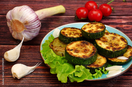 Fried zucchini with garlic and tomatoes on a wooden table