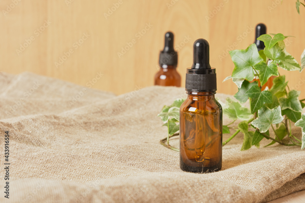 Brown glass bottle dropper with cosmetic oil and plant Brown glass bottle dropper with cosmetic oil and plant