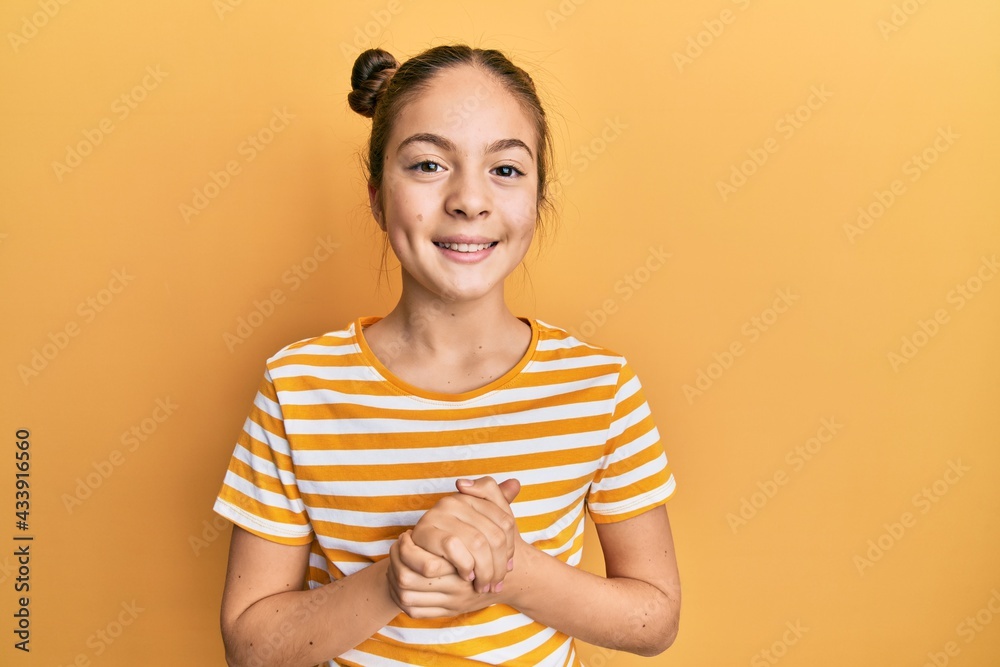 Beautiful brunette little girl wearing casual striped t shirt with hands together and crossed fingers smiling relaxed and cheerful. success and optimistic Beautiful brunette little girl wearing casual striped t shirt with hands together and crossed fingers smiling relaxed and cheerful. success and optimistic
