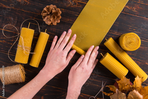 Photography Women's hands make handmade candles of natural wax with texture of honeycomb bees, on a wooden table