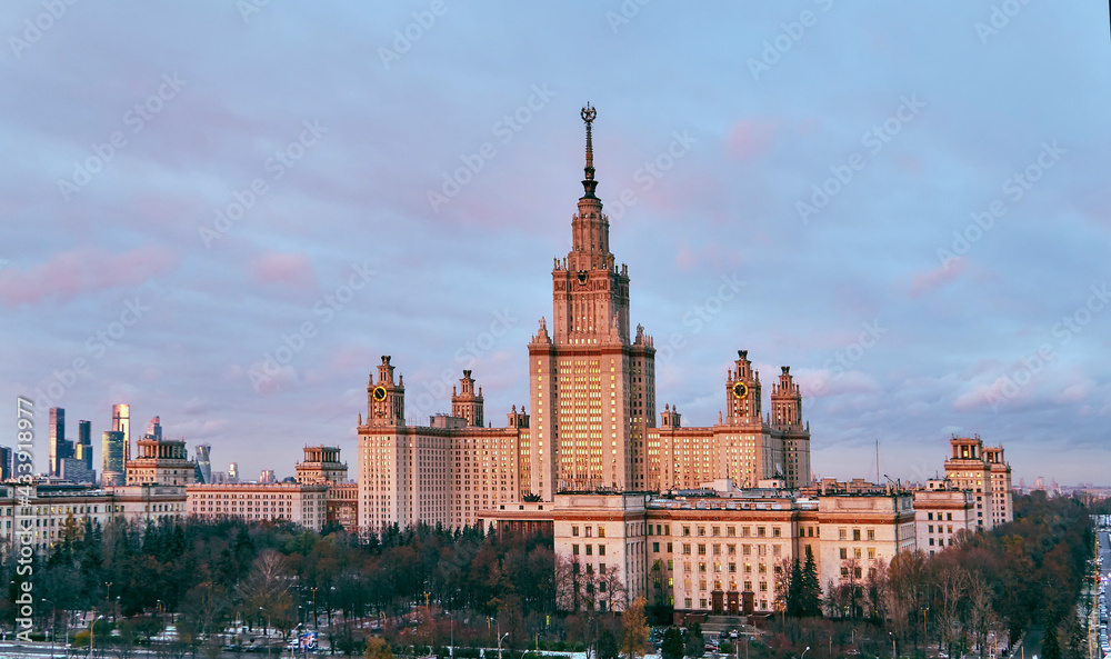 Fototapeta premium Aerial panoramic view of sunset campus buildings of famous Moscow university under dramatic cloudy sky in spring with sunlight reflections in windows