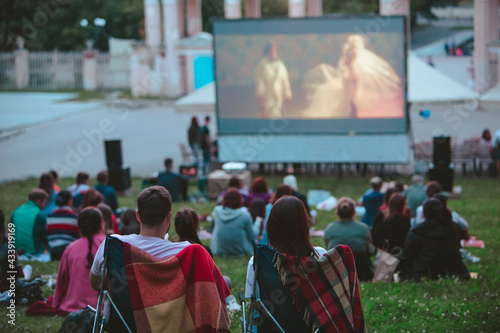 couple sitting in camp chairs in front of movie screen at open air cinema