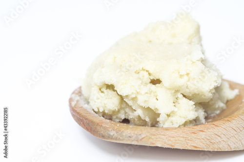 Shea butter isolated on white background on wooden spoon, unrefined, close up
