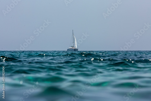 White sailing boat catamaran on ocean near beach. photo