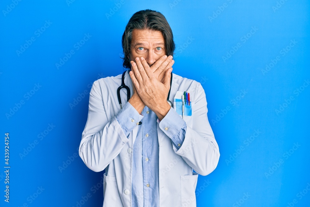 Middle age handsome man wearing doctor uniform and stethoscope shocked covering mouth with hands for mistake. secret concept. Middle age handsome man wearing doctor uniform and stethoscope shocked covering mouth with hands for mistake. secret concept.