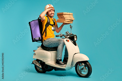 Young courier, pizza delivery man in uniform with thermo backpack on a moped isolated on blue background. Fast transport express home delivery. Online order.