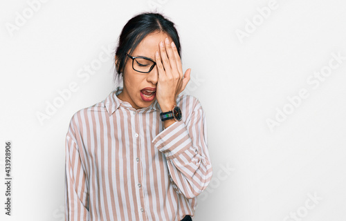 Young hispanic girl wearing casual clothes and glasses yawning tired covering half face, eye and mouth with hand. face hurts in pain.