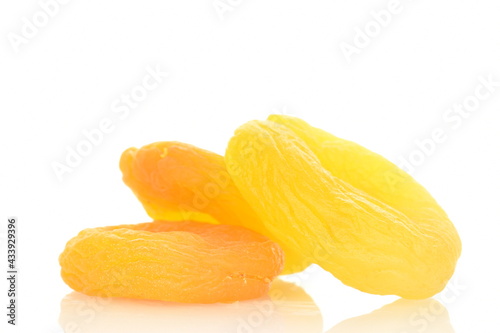 Several bright golden dried apricots, close-up, isolated on white.