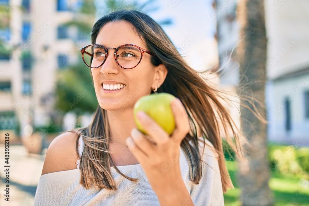 Young caucasian woman smiling happy eating green apple at the city. Young caucasian woman smiling happy eating green apple at the city.