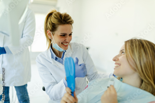 Female dentist showing to patient that everything is ok after dental examination.
