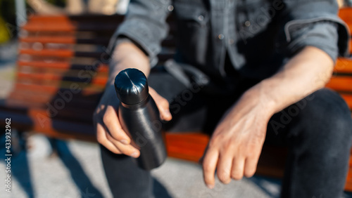Close-up of male hands, holding steel reusable thermo water bottle of black. Eco bottles, zero waste, no plastic.