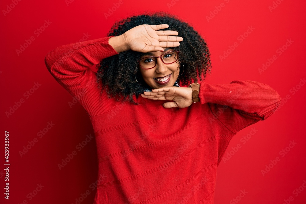 Beautiful african american woman with afro hair wearing sweater and glasses smiling cheerful playing peek a boo with hands showing face. surprised and exited