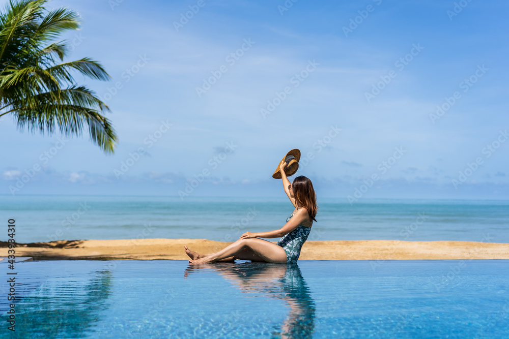 Young woman traveler relaxing and enjoying by a tropical resort pool while traveling for summer vacation, Travel concept