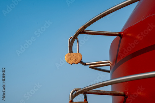 Metal rusty padlock in the shape of a heart, hanged by lovers on a background of blue sky (825)