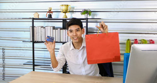 Asian man blogger broadcasting a video for selling product online .Shopping online and payment with credit card concept at home