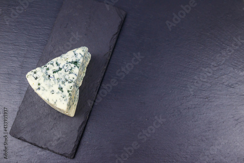 Blue cheese with mold on black slate background. Top view, copy space