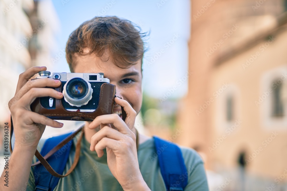 Young caucasian tourist man smiling happy using vintage camera at the city.