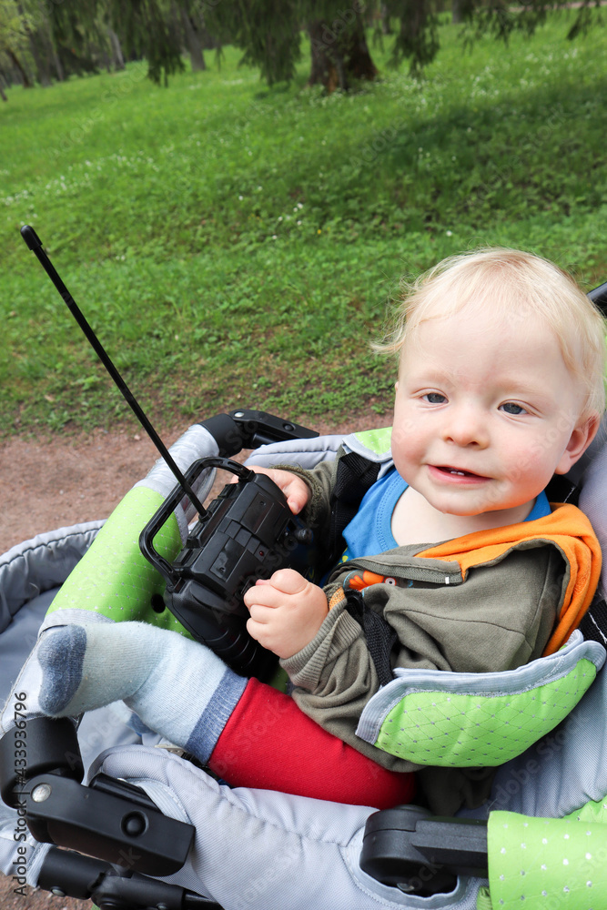 child playing with a toy car remote in a stroller child playing with a toy car remote in a stroller