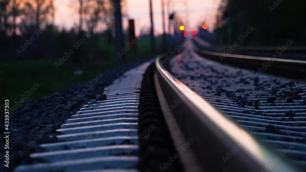 Dreamy low angle view of railroad tracks disappearing in the distance at sunset. Concept of travel and unknown destination. Dolly right.