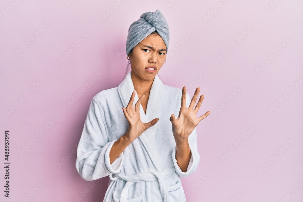 Young chinese woman wearing shower towel cap and bathrobe disgusted expression, displeased and fearful doing disgust face because aversion reaction. with hands raised Young chinese woman wearing shower towel cap and bathrobe disgusted expression, displeased and fearful doing disgust face because aversion reaction. with hands raised